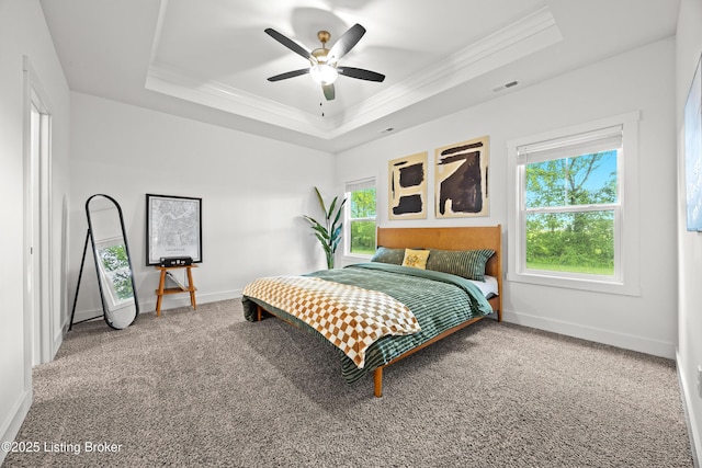 carpeted bedroom with a raised ceiling, crown molding, baseboards, and ceiling fan