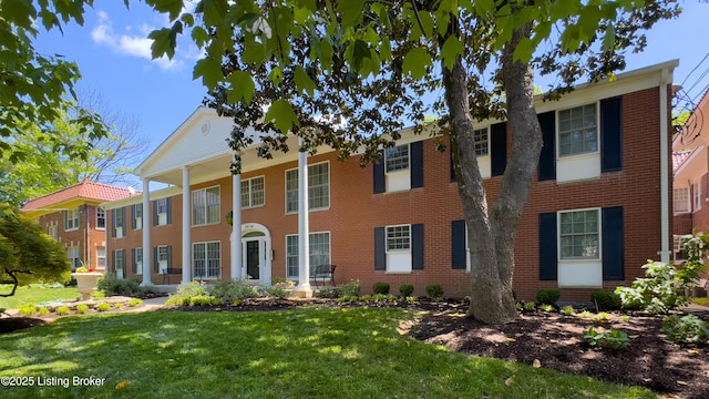 neoclassical home with a front lawn and brick siding