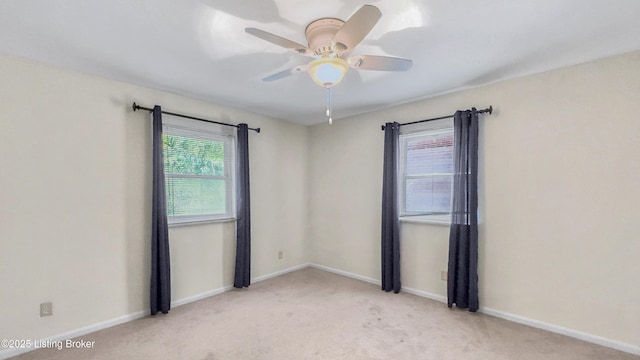 carpeted spare room featuring ceiling fan and baseboards