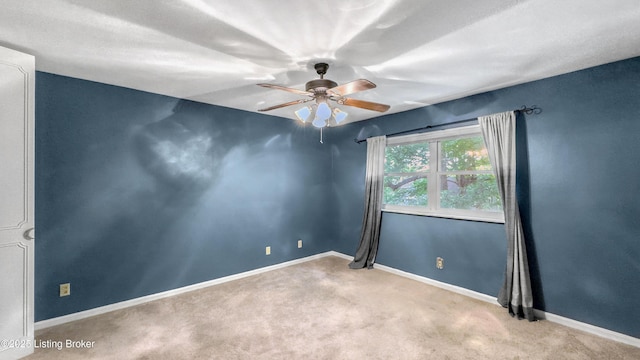 carpeted spare room featuring a ceiling fan and baseboards