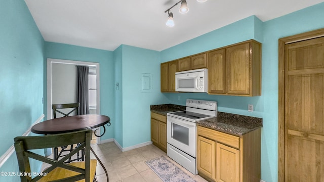 kitchen featuring white appliances, light tile patterned floors, baseboards, and dark stone countertops