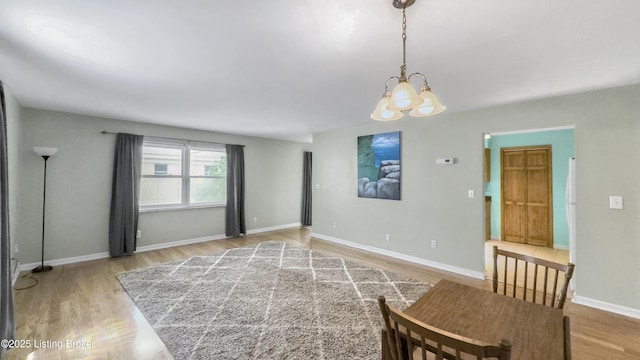 unfurnished living room with wood finished floors, a chandelier, and baseboards