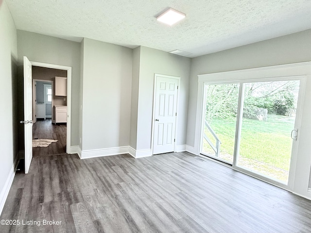 713 E Hill St, Louisville, KY 40217 - empty room featuring wood finished floors, baseboards, and a textured ceiling