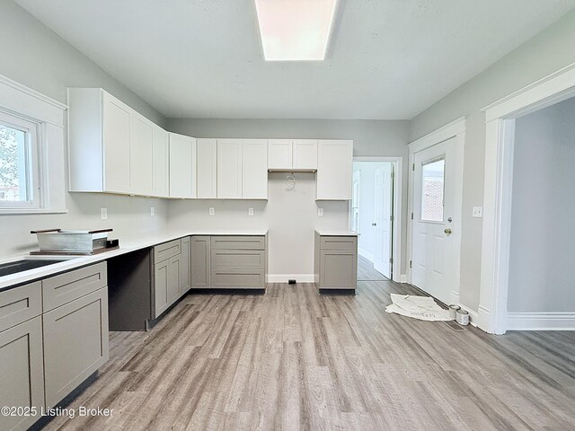 713 E Hill St, Louisville, KY 40217 - kitchen with gray cabinetry, light wood-type flooring, and baseboards