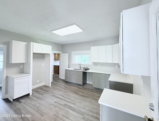 713 E Hill St, Louisville, KY 40217 - kitchen with a sink, light wood finished floors, white cabinets, light countertops, and gray cabinetry