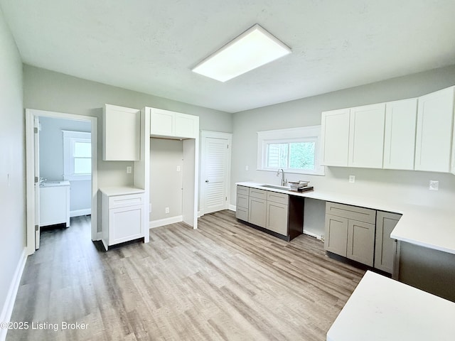 713 E Hill St, Louisville, KY 40217 - kitchen featuring light wood finished floors, white cabinets, light countertops, and baseboards