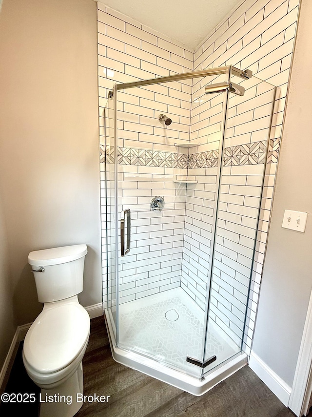 713 E Hill St, Louisville, KY 40217 - full bathroom with wood finished floors, a shower stall, baseboards, and toilet