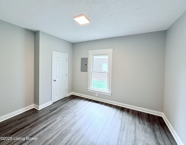 713 E Hill St, Louisville, KY 40217 - empty room with dark wood finished floors, electric panel, baseboards, and a textured ceiling