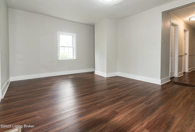 unfurnished room with dark wood finished floors and baseboards