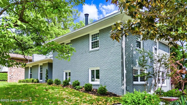 view of side of home featuring brick siding and a lawn