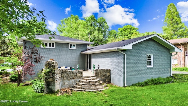 rear view of property featuring a lawn and brick siding