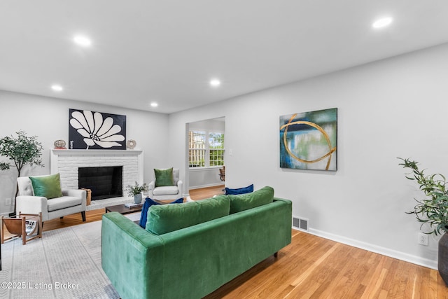 living room featuring a fireplace, baseboards, light wood-style floors, and recessed lighting