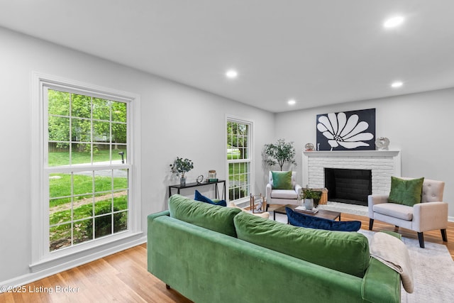 living room featuring a brick fireplace, recessed lighting, and light wood-type flooring