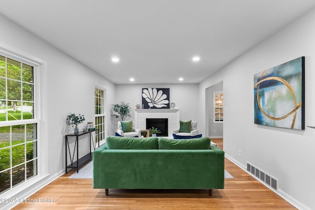 living room featuring a fireplace, light wood finished floors, recessed lighting, and baseboards