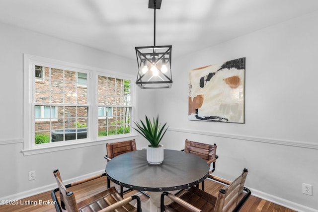 dining area featuring baseboards, a chandelier, and wood finished floors