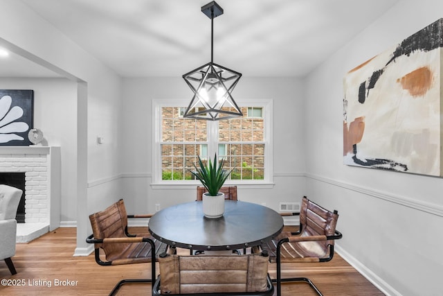 dining space with light wood-type flooring, baseboards, and a fireplace