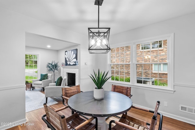 dining area with a chandelier, wood finished floors, a brick fireplace, and baseboards