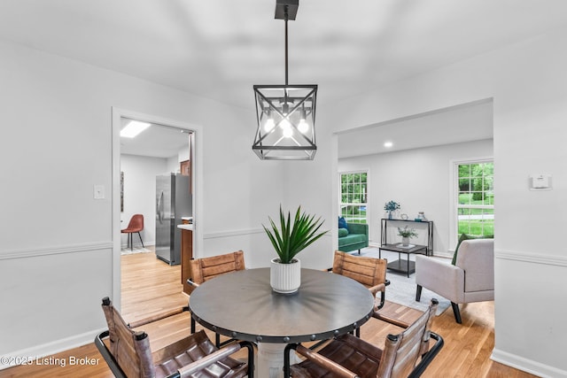 dining area featuring light wood finished floors, a chandelier, and baseboards
