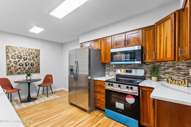 kitchen featuring stainless steel appliances, light wood-type flooring, backsplash, light countertops, and brown cabinets