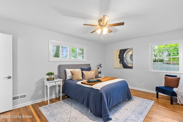 bedroom with multiple windows, wood finished floors, baseboards, and a ceiling fan