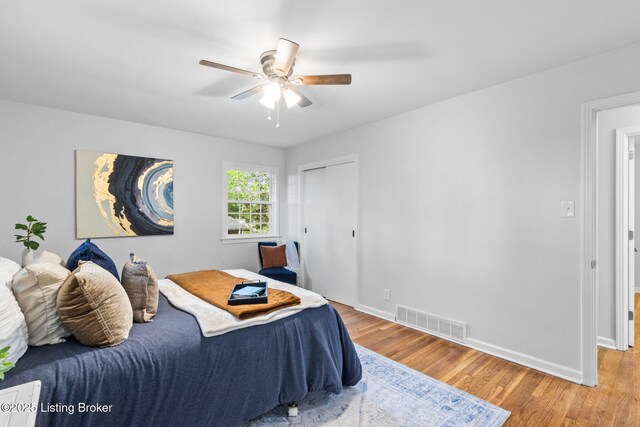 bedroom with light wood finished floors, baseboards, a ceiling fan, and a closet