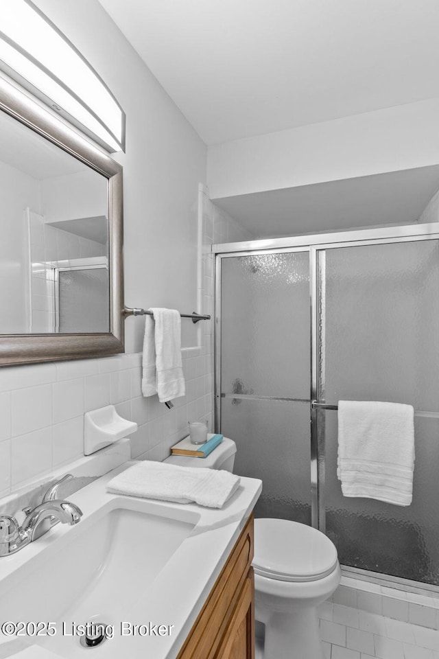 bathroom featuring a shower stall, tile walls, vanity, and toilet