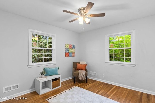 living area featuring healthy amount of natural light, wood finished floors, and baseboards