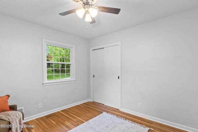 unfurnished room featuring wood finished floors, baseboards, and ceiling fan