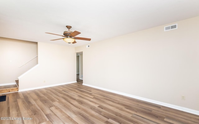 spare room featuring a ceiling fan, baseboards, and wood finished floors