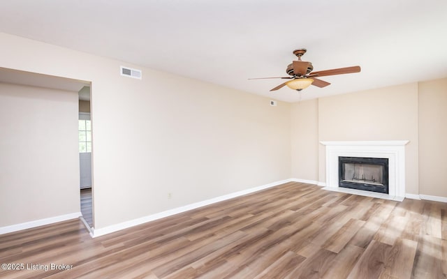 unfurnished living room with wood finished floors, baseboards, and ceiling fan