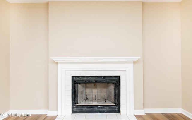 detailed view of a fireplace, baseboards, and wood finished floors