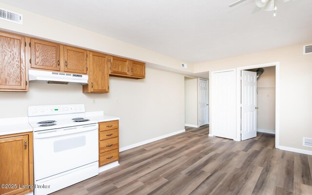 kitchen with white range with electric stovetop, under cabinet range hood, light countertops, and wood finished floors