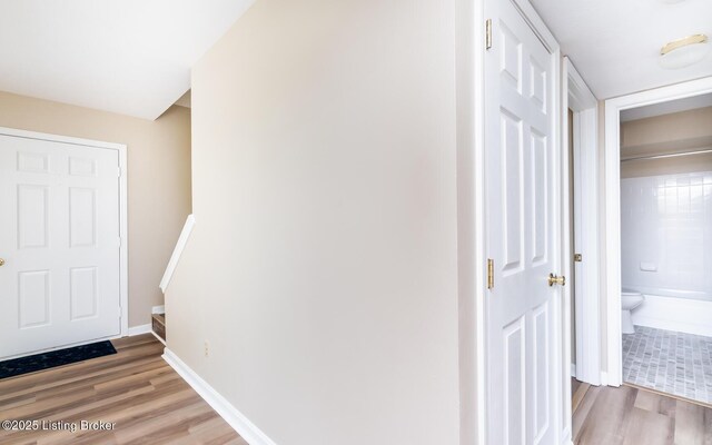 corridor with light wood-style floors and baseboards