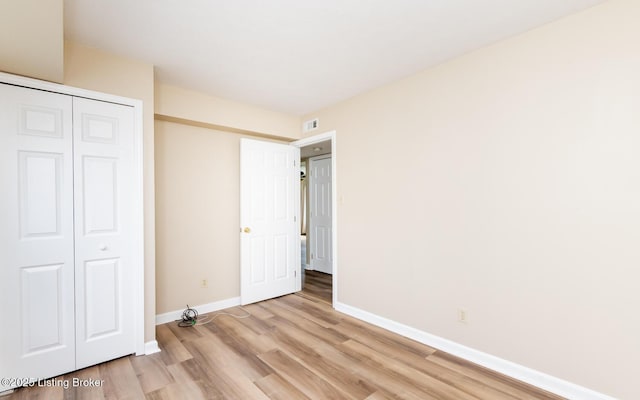 unfurnished bedroom with baseboards, light wood-type flooring, and a closet