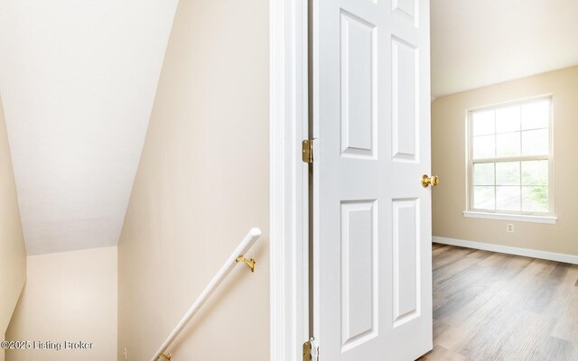 staircase featuring wood finished floors and baseboards