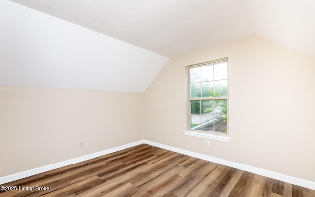 additional living space with lofted ceiling, wood finished floors, and baseboards