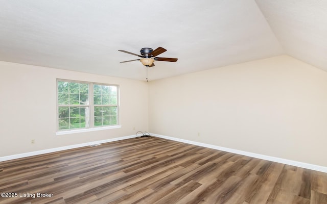 spare room featuring wood finished floors, ceiling fan, baseboards, and lofted ceiling