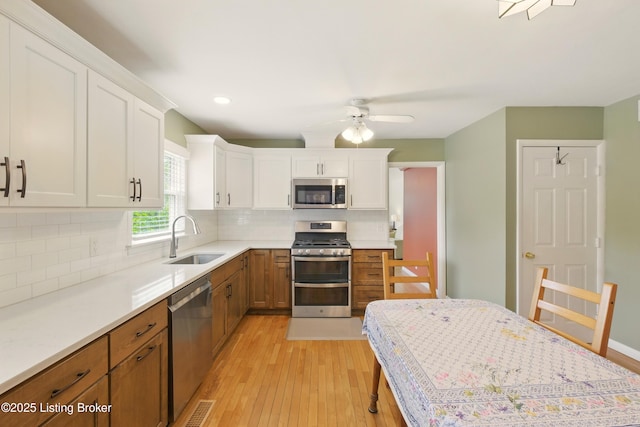 3745 Rosemont Blvd, Louisville, KY 40218 - kitchen with a sink, stainless steel appliances, light wood finished floors, white cabinetry, and light countertops