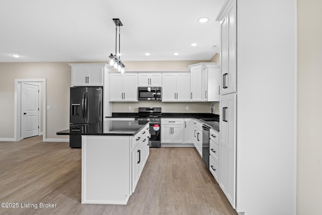 kitchen featuring appliances with stainless steel finishes, dark countertops, light wood-type flooring, a kitchen island, and a sink