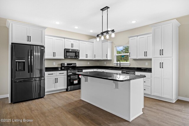 kitchen with stainless steel appliances, a sink, dark countertops, white cabinetry, and recessed lighting