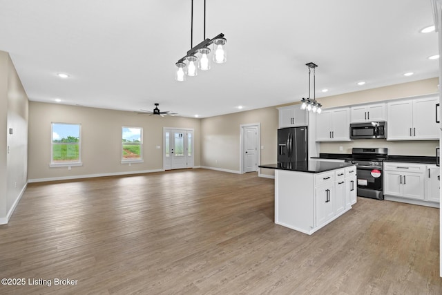 kitchen with appliances with stainless steel finishes, a center island, recessed lighting, open floor plan, and light wood-style flooring