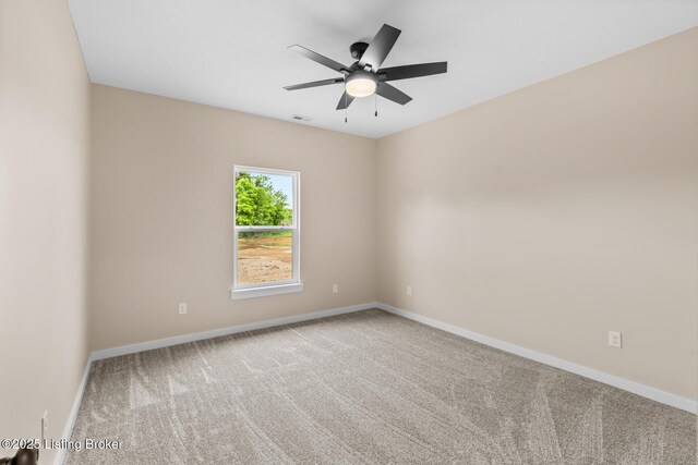 carpeted spare room featuring baseboards and a ceiling fan