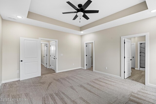 unfurnished bedroom featuring carpet flooring, recessed lighting, baseboards, and a raised ceiling