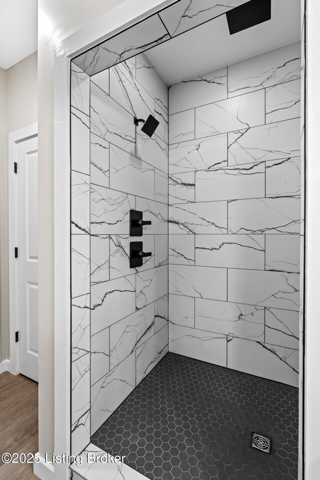 bathroom with a tile shower and wood finished floors