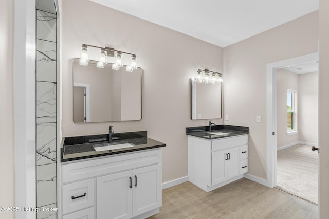 full bath with two vanities, wood finished floors, and baseboards