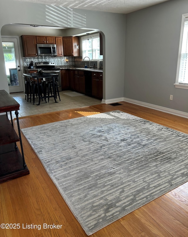 4908 Fielding Way, Louisville, KY 40216 - kitchen featuring arched walkways, appliances with stainless steel finishes, baseboards, and healthy amount of natural light