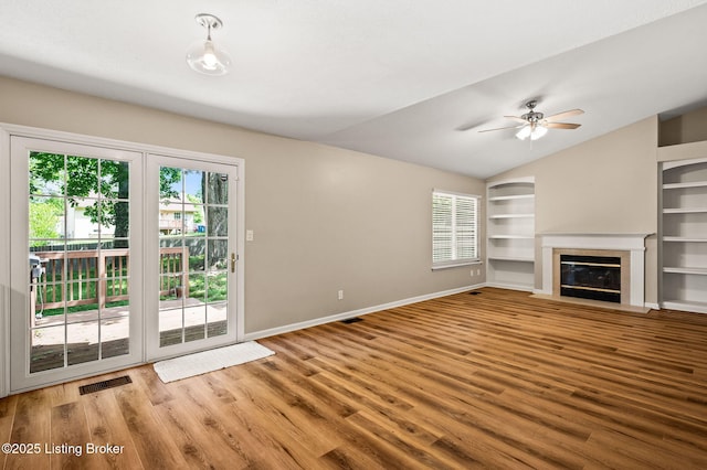 10707 Hickory Cove Ct, Louisville, KY 40245 - unfurnished living room featuring built in shelves, healthy amount of natural light, wood finished floors, and vaulted ceiling