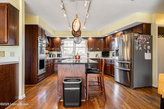 1309 S Buckeye Ln, Goshen, KY 40026 - kitchen featuring appliances with stainless steel finishes, dark wood-style flooring, a center island, and a breakfast bar area