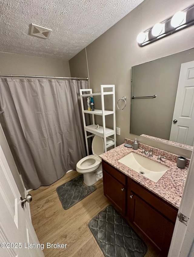 2512 S 4th St, Louisville, KY 40208 - bathroom with wood finished floors, toilet, a textured ceiling, vanity, and a shower with curtain