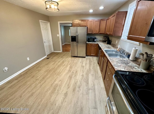 2512 S 4th St, Louisville, KY 40208 - kitchen featuring stainless steel appliances, a sink, brown cabinetry, light wood finished floors, and a textured ceiling